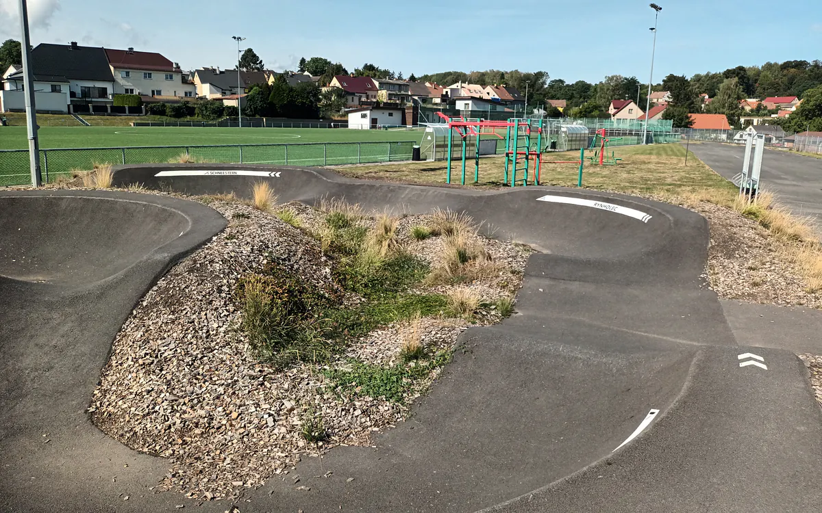 Pumptrack v sousedství fotbalového hřiště a workoutu